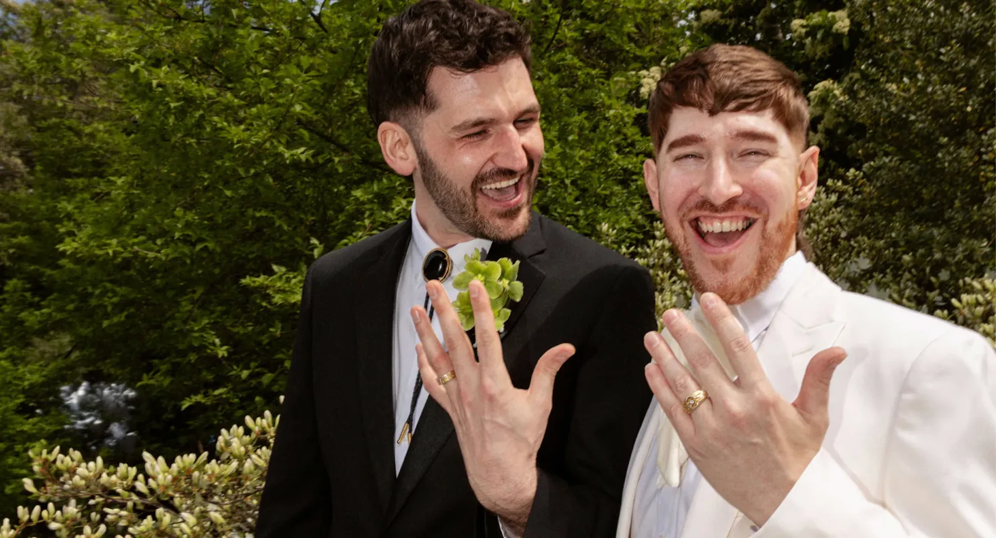 Two grooms laughing and showing off their wedding rings